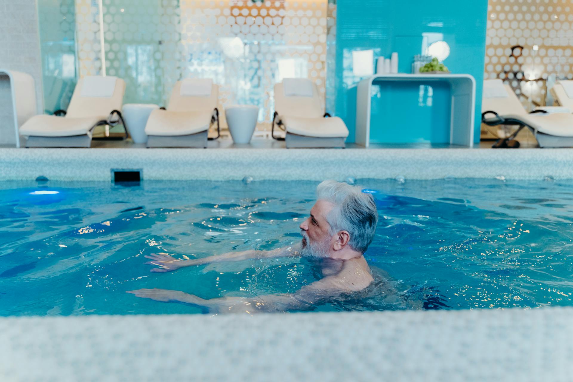 Older man swimming in a home swimming pool looking relaxed.